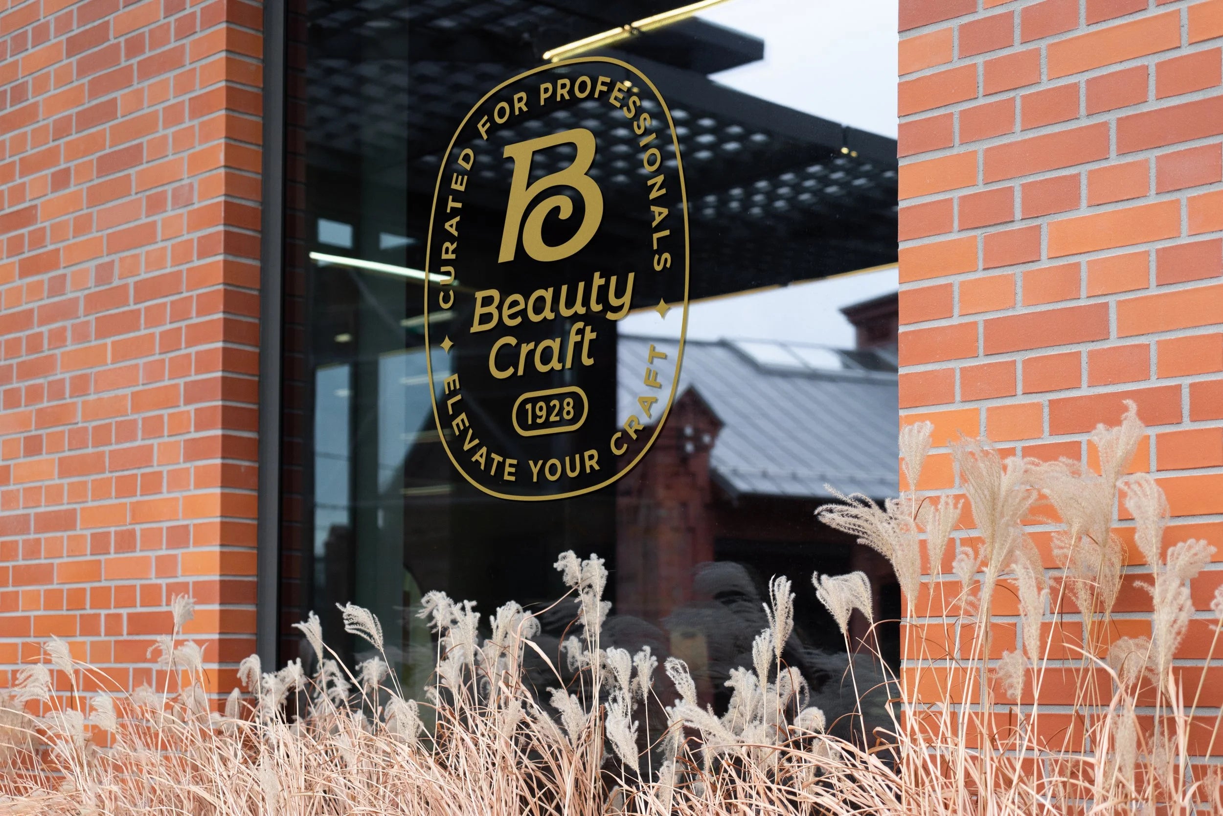 Beauty Craft logo on a glass window with a brick wall and plants in the foreground
